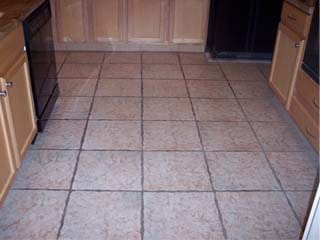 A dirty kitchen floor of ceramic tile in Mesa, Arizona, before quality cleaning service by Desert Tile & Grout Care